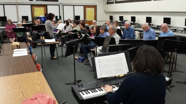 At a recent rehearsal, Denise Bastanza directs the chorus, accompanied on the keyboard by Helga Bartus.