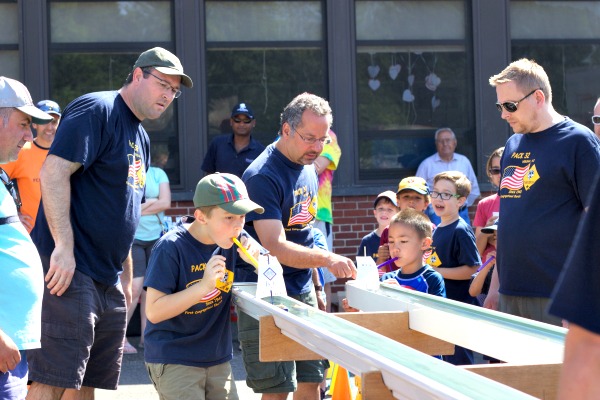 George Donnelly and Evan Tsang are off to the races as Cub Scout leaders Brian Donnelly, Mark Ali and Russ Williamson officiate the race.