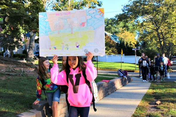 Angelie Sin proudly displays her poster as she walks to Forest Avenue School.
