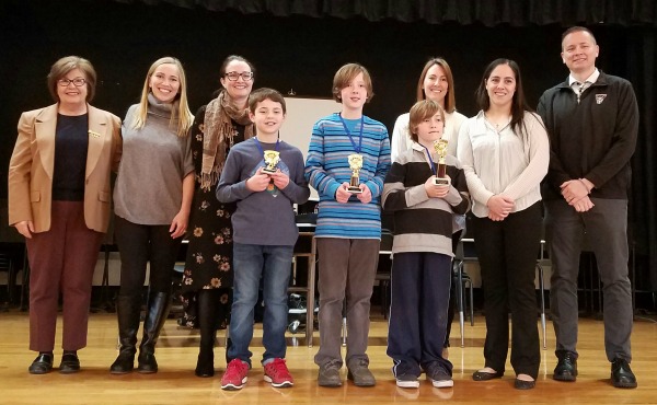 The spelling bee winners, judges, and coordinators pose for a picture. (From left to right)  Cheryl Ashley, Joanna Rybak, Corisa Walker, Owen Chanana, Stephen Gaffney, Erika Grothues, Diana Weeks, and Charles Miller.