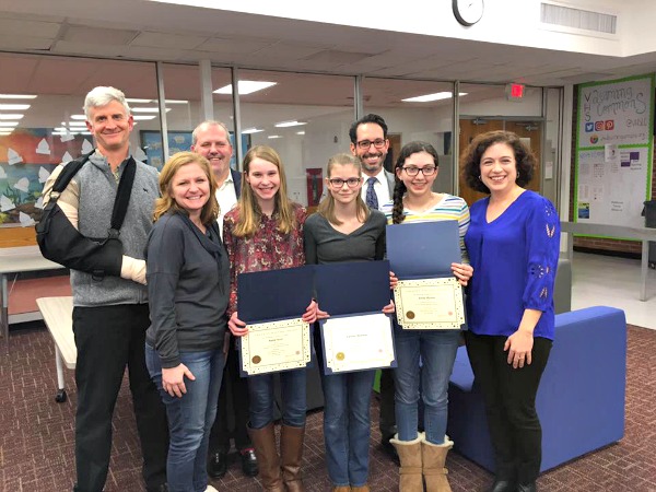 The winners of the Verona Junior's creative writing contest (center) are first place winner Katie Hunt, third place winner Eleanor Newman, and second place winner Emily Wynne with Board of Education members James Day and Glen Elliot, Verona School Business Administrator Cheryl Nardino, Verona Public Schools Superintendent Rui Dionisio, and Arts Creative Co-Chair Christine McGrath.